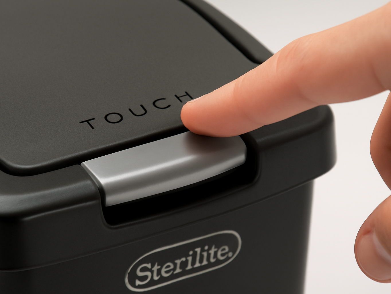 Close-up of black wastebasket lid with touch-activation sensor, finger about to tap the opening mechanism